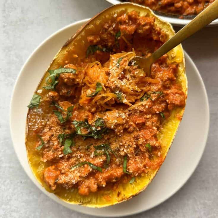 Baked acorn squash filled with seasoned meat and vegetables, garnished with herbs.