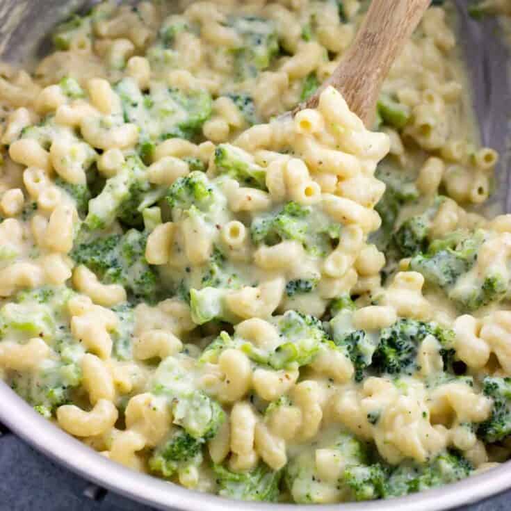 Close-up of creamy broccoli mac and cheese with a wooden spoon in a bowl.