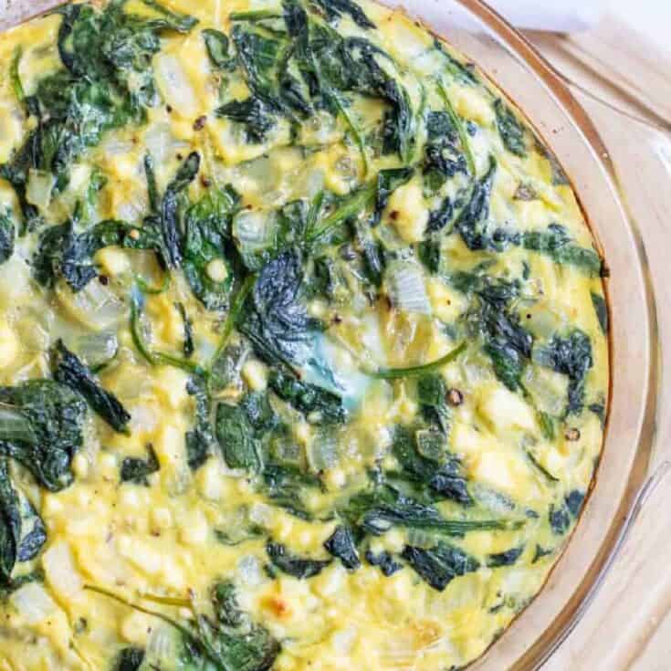 Creamy spinach and cheese casserole baked in a glass dish.
