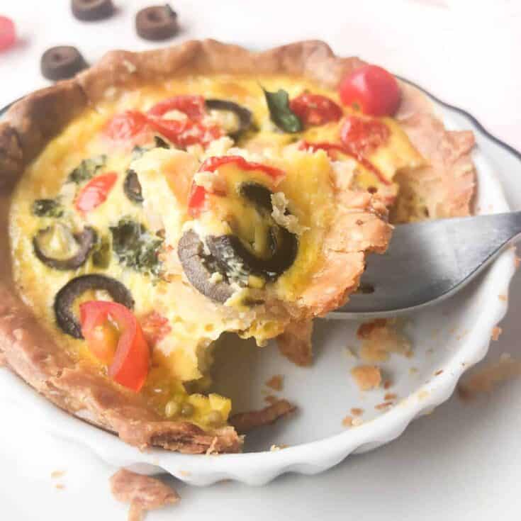 Delicious savory egg quiche with tomatoes, olives, and cheese in a flaky crust.