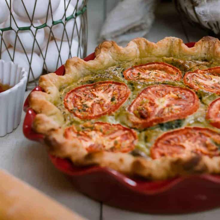 Delicious homemade tomato and herb quiche in a red ceramic dish.