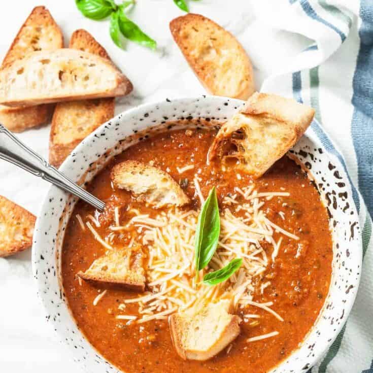 Creamy tomato basil soup with shredded cheese and toasted baguette slices.