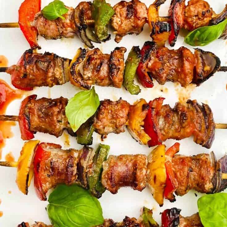 Skewered grilled chicken and vegetable kebabs with fresh basil leaves.