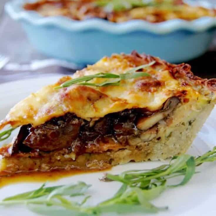 Rich vegetable lasagna with cheese and herbs on white plate.