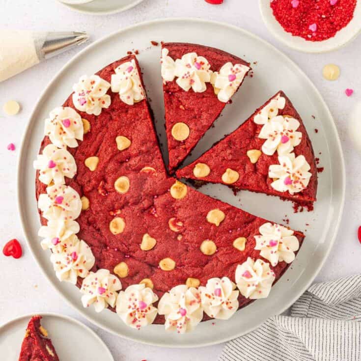 Delicious red velvet cake decorated with white frosting flowers and pink sprinkles.