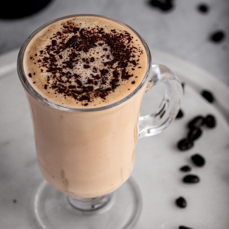Creamy coffee drink with chocolate shavings in a glass mug.