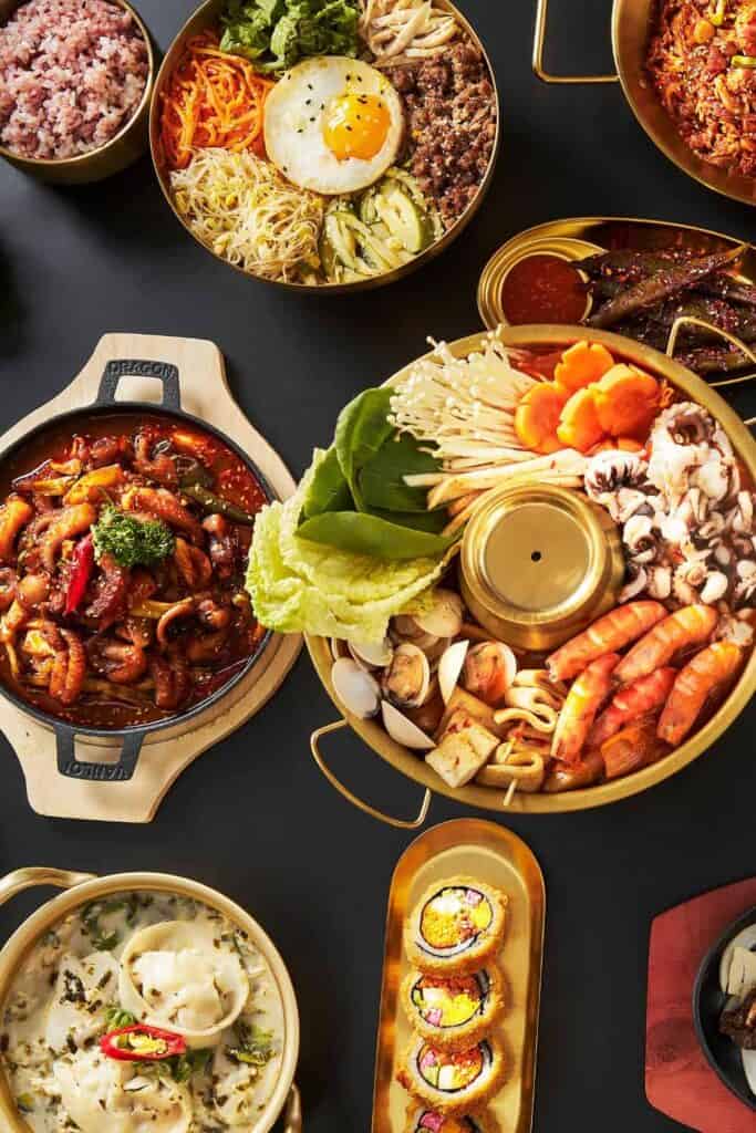 Assorted Asian fusion dishes served on black table, vibrant and colorful presentation.