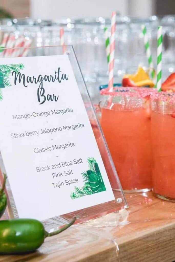Bright pink margarita drinks with salt rims and decorative straws served at a tropical bar.