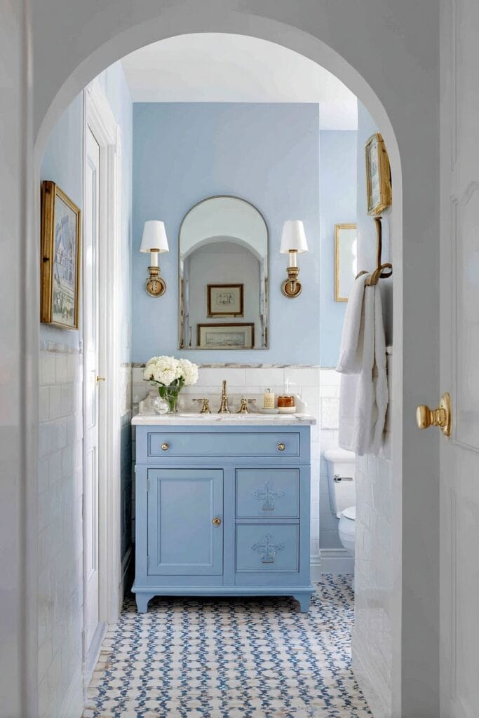 Cozy blue vintage bathroom with elegant mirror and floral decor at The Olive Branch Nest.
