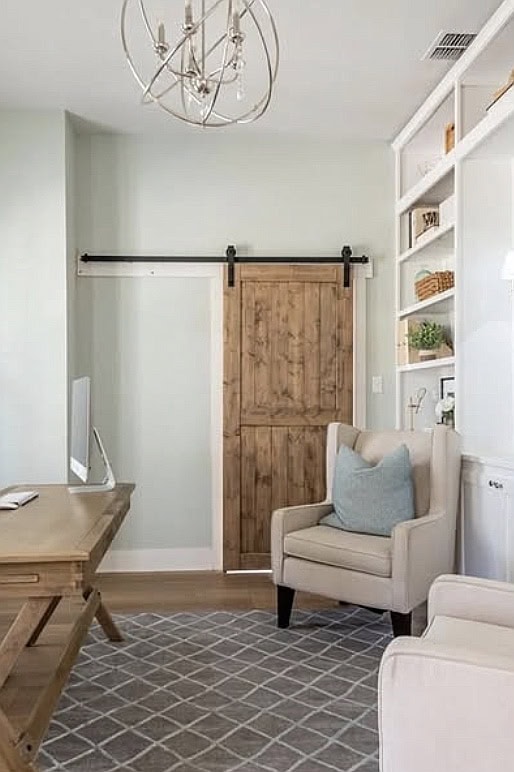 Rustic wooden sliding barn door in cozy office space.