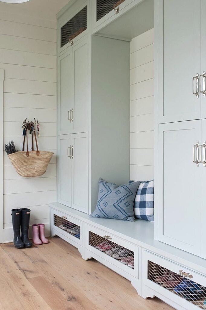 Cozy mudroom with built-in white cabinets and plaid accent pillows.