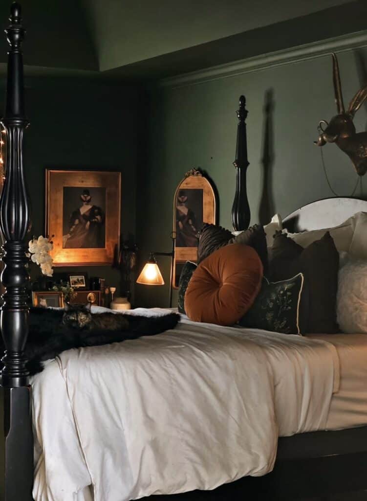 Cozy bedroom with dark green walls, elegant mirror, and plush pillows.