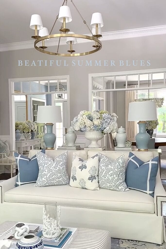 Bright living room interior with blue and white pillows, floral accents, and elegant lighting.