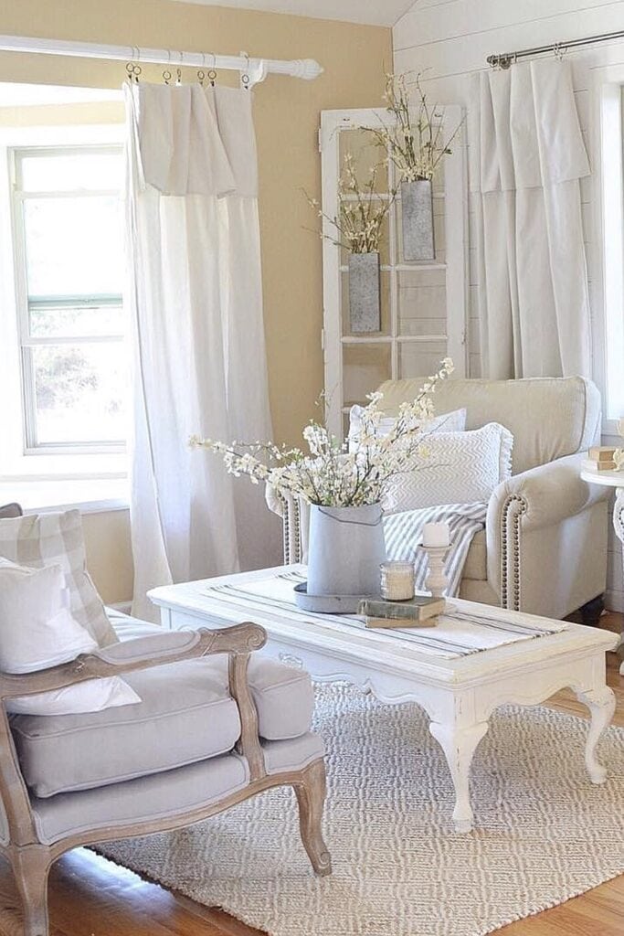 Elegant white living room with vintage-style furniture and fresh flowers.