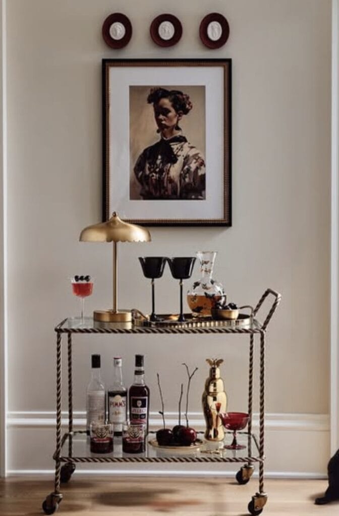 Stylish home bar cart with gold accents and mixed drinks setup.