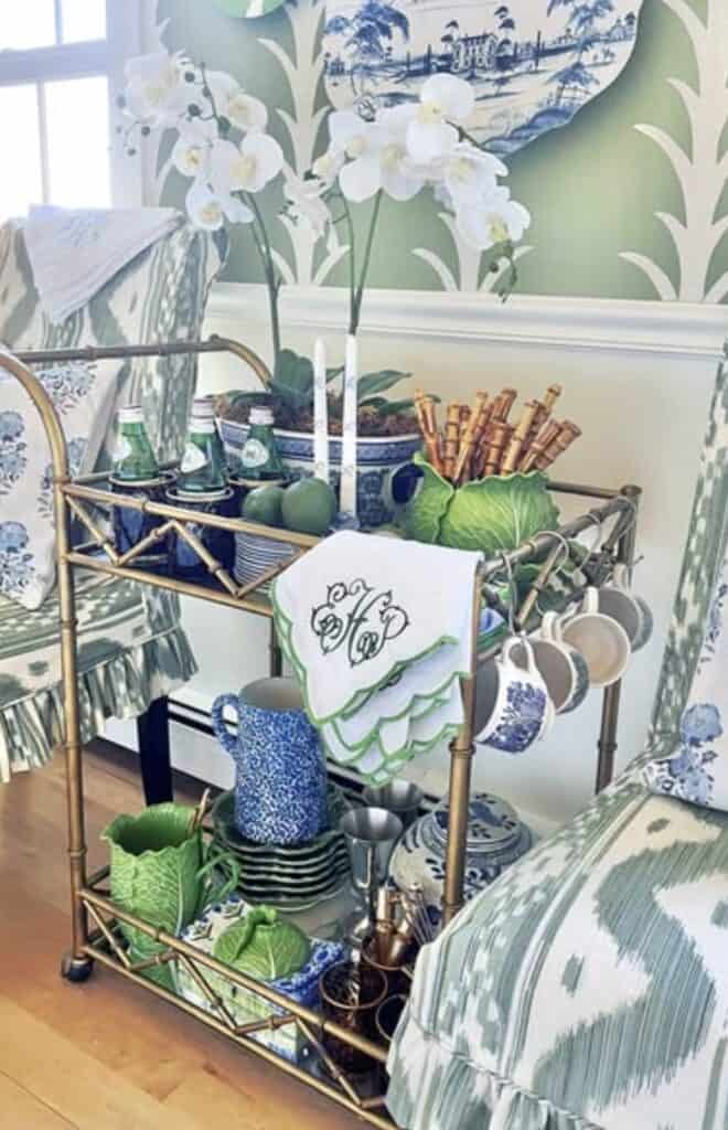 Ornate gold bar cart styled with blue, green, and white dishware, perfect for home bar setups.