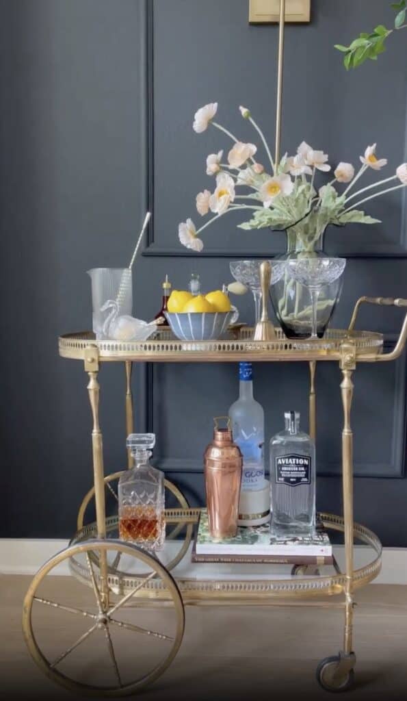Clean, stylish bar cart with glassware and floral arrangement.