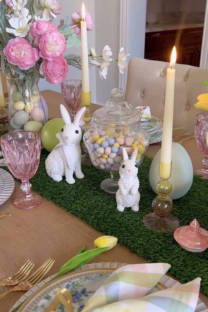 Elegant Easter table decor with pink flowers, candles, and pastel accents for spring celebrations.