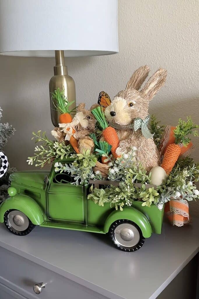 Cute bunny figurine with Easter carrots & flowers in green toy truck.