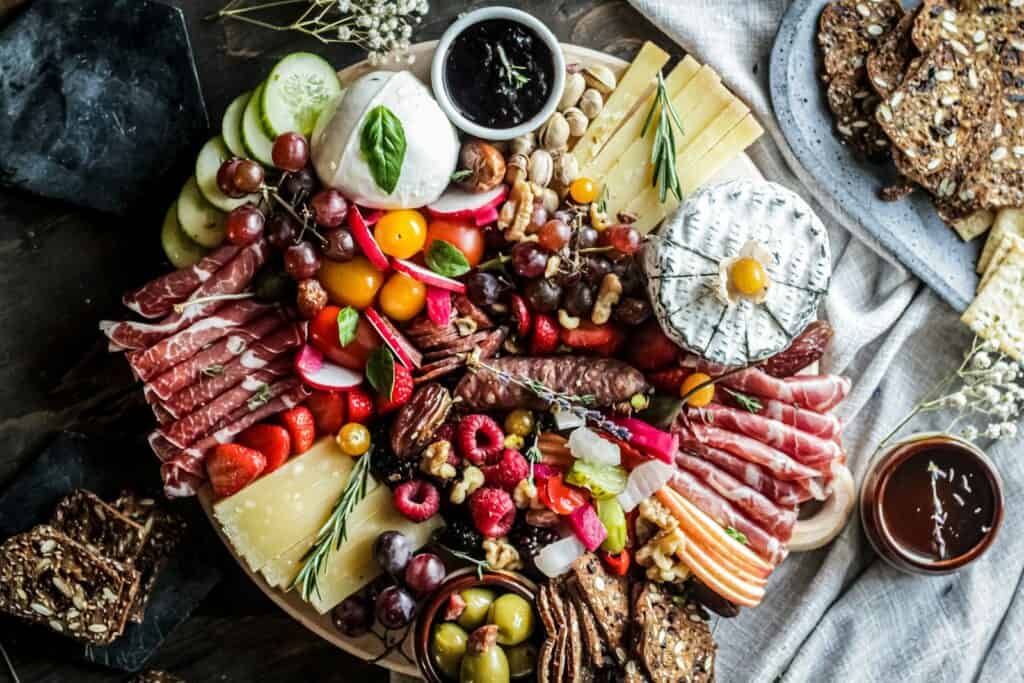 Delicious cheese and cured meats with fresh fruit and nuts on a serving board.