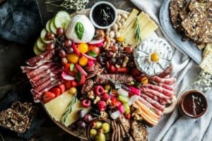Delicious cheese and cured meats with fresh fruit and nuts on a serving board.