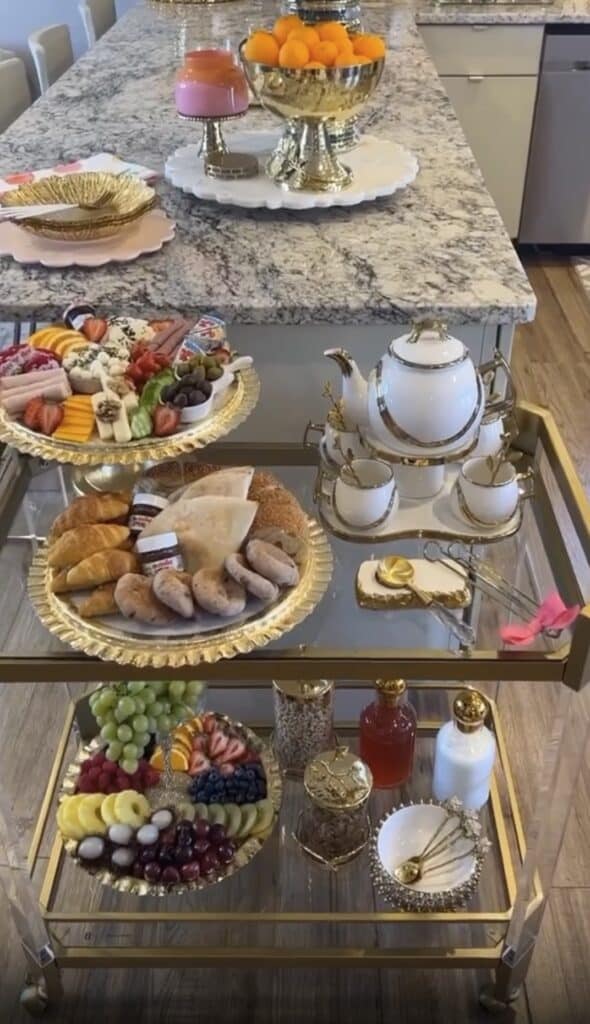 Gold bar cart with desserts, fruits, and beverages for home entertaining.