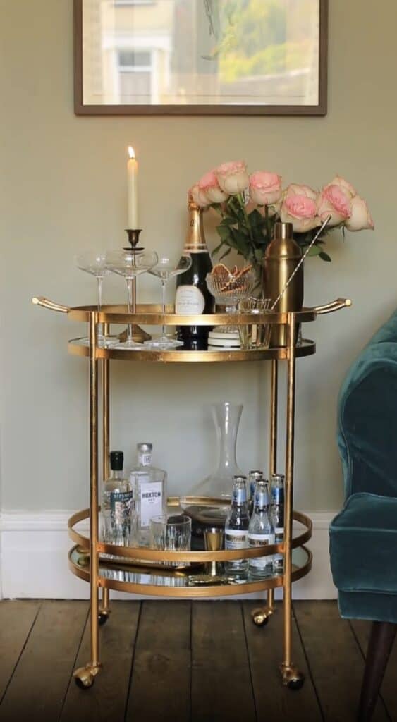 Elegant gold bar cart with pink roses and champagne for high-end decor.
