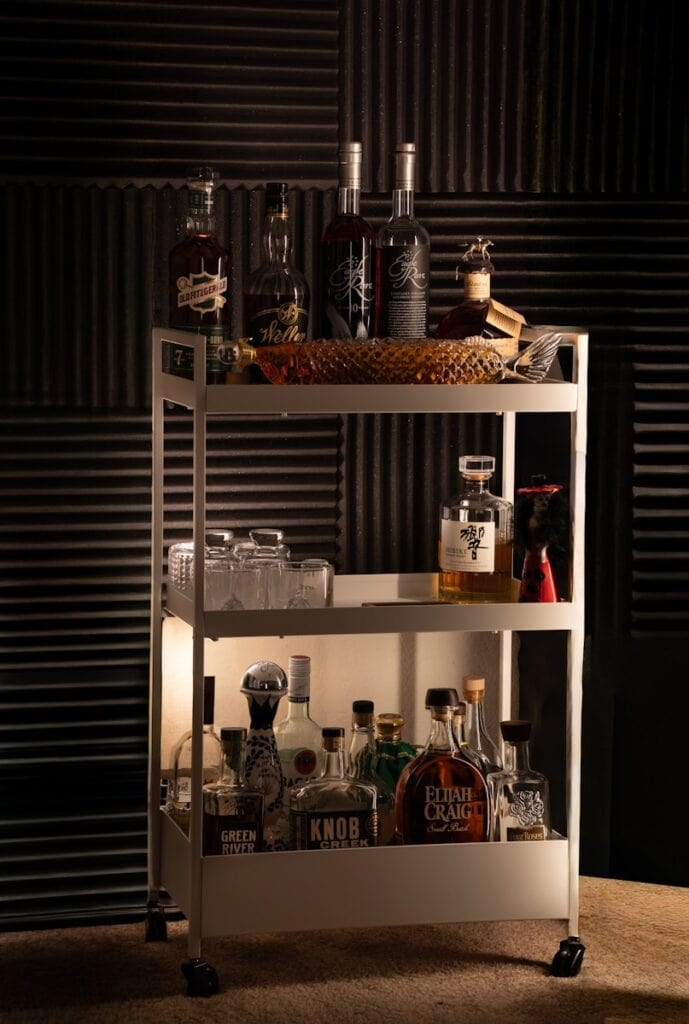 Stylish bar cart featuring assorted liquor bottles, glassware, and accessories for a modern living r.