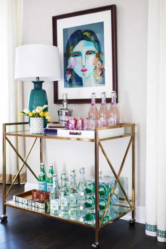 Stylish home bar cart with glass bottles, artwork, and decorative accessories.