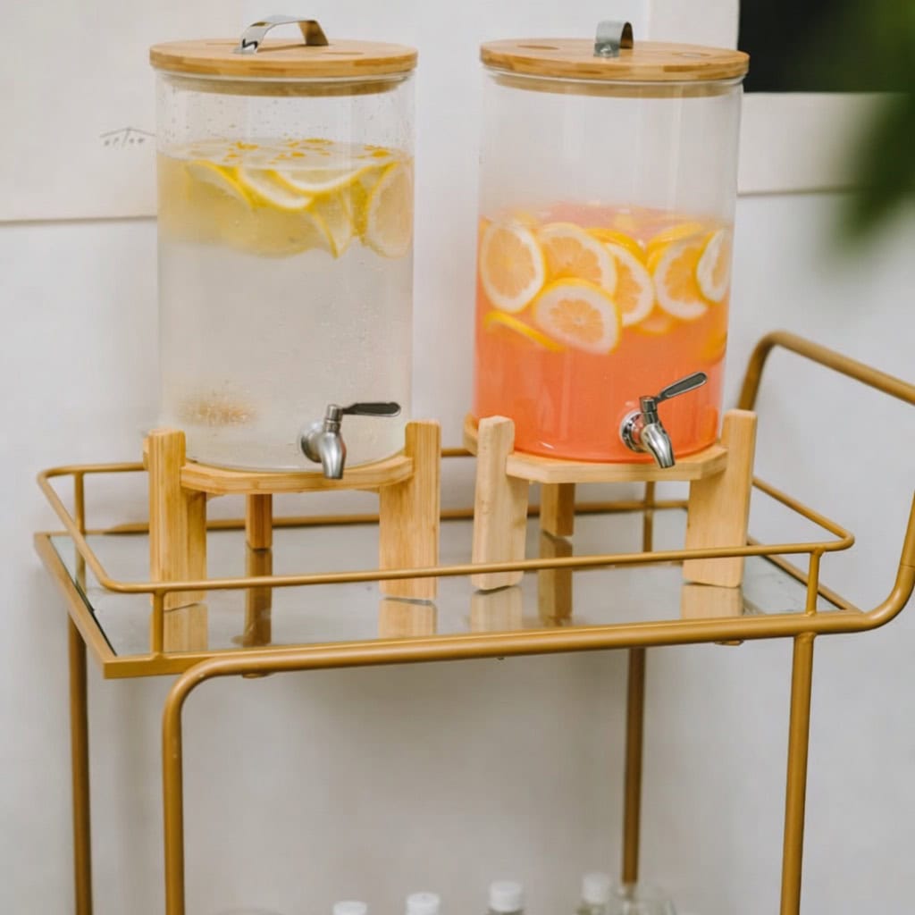Two glass beverage dispensers with lemon and orange slices, on a gold bar cart.