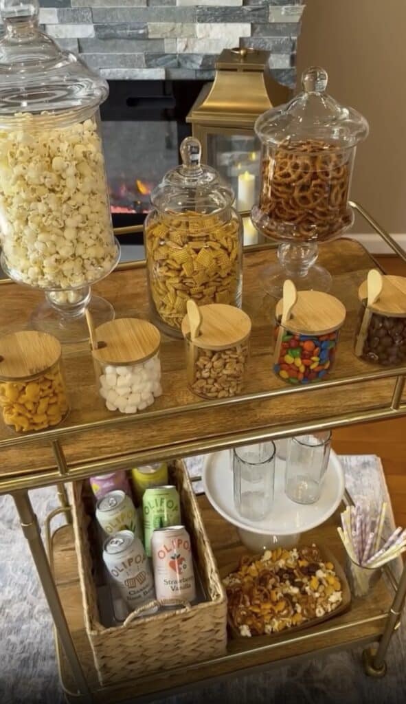 Elegant bar cart with jars of popcorn, candies, and beverages for home entertaining.