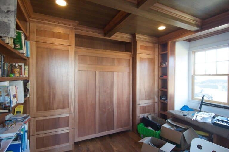Modern Murphy bed setup in a cozy home office with wooden cabinetry and workspace.