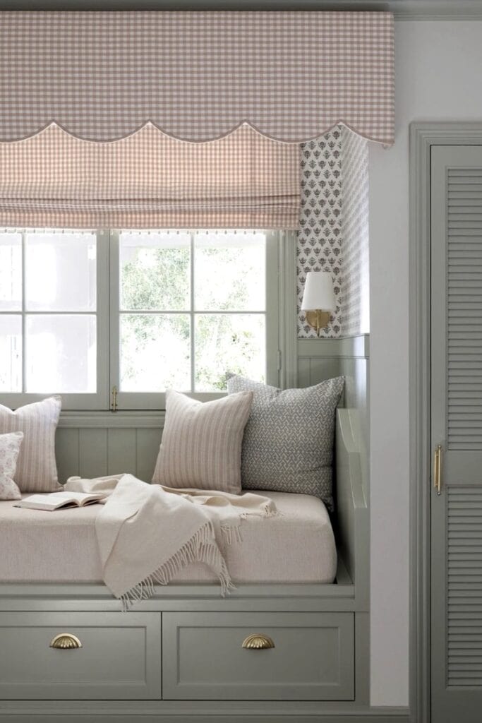 Bright bedroom with built-in window seat, soft pillows, and charming window treatments.