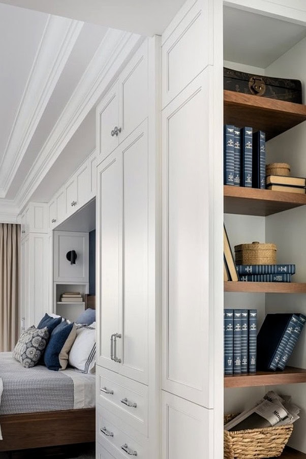 Built-in bedroom storage with white cabinetry and wooden shelves for organization.