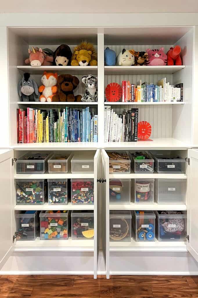 Built-in playroom storage with plush toys, books, and labeled bins for kids.