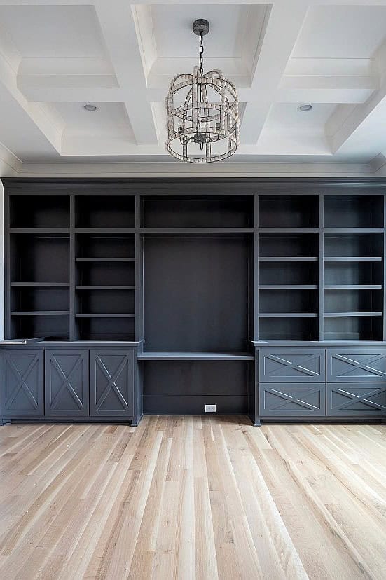 Built-in dark gray shelving unit with storage cabinets in a modern room.