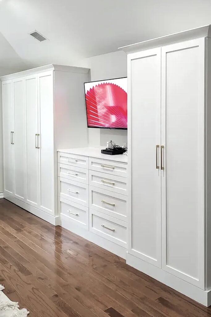 Elegant built-in white bedroom storage with drawers and wardrobe.