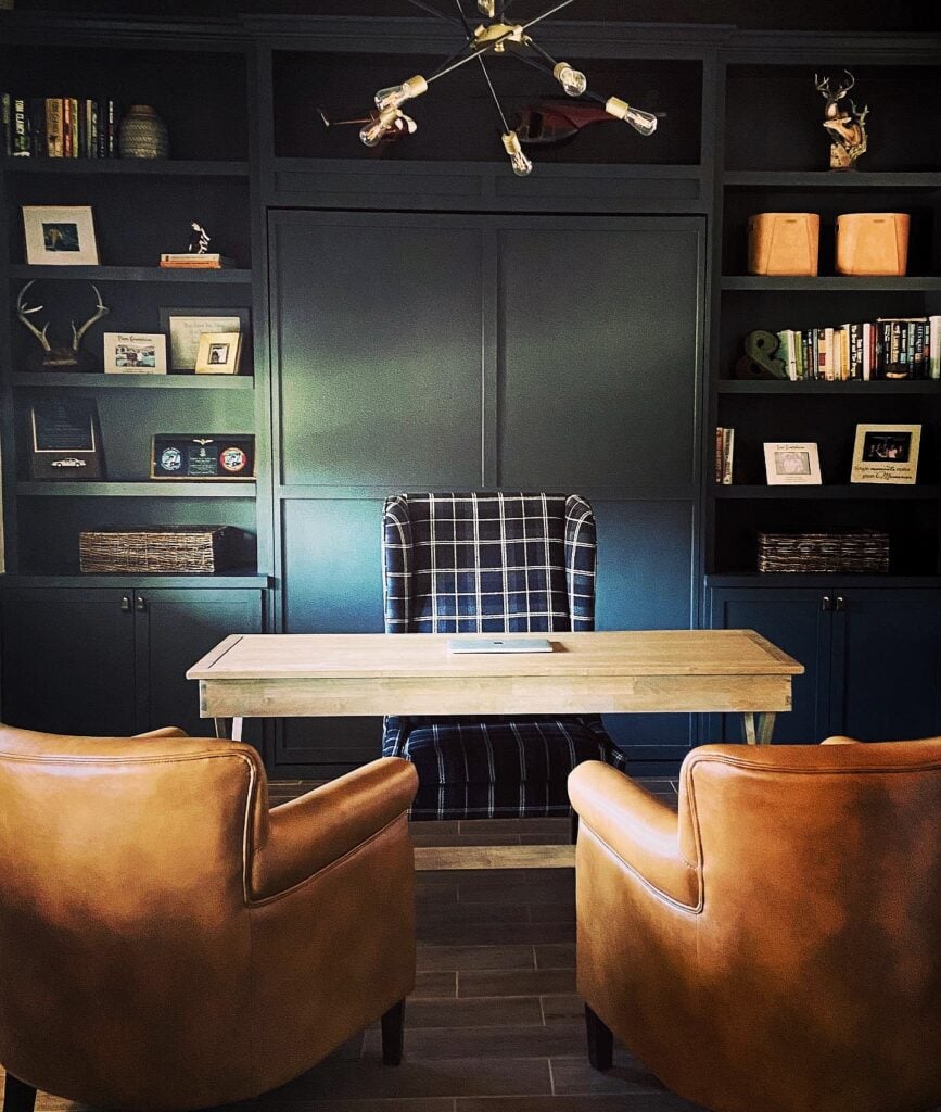 Cozy office space with Murphy bed, bookshelves, and comfortable seating for work and relaxation.