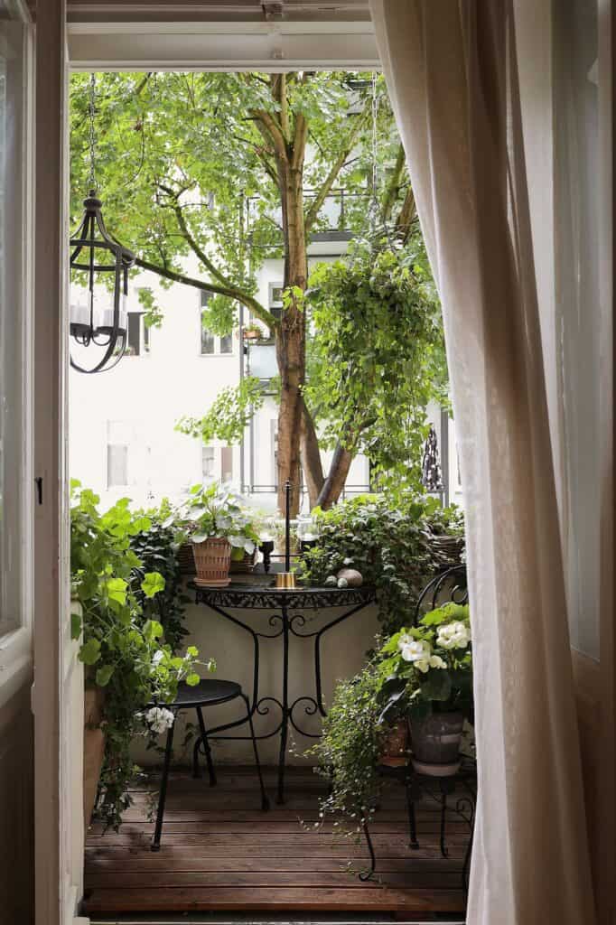 A cozy balcony garden with a planter box, lush greenery, and outdoor seating.