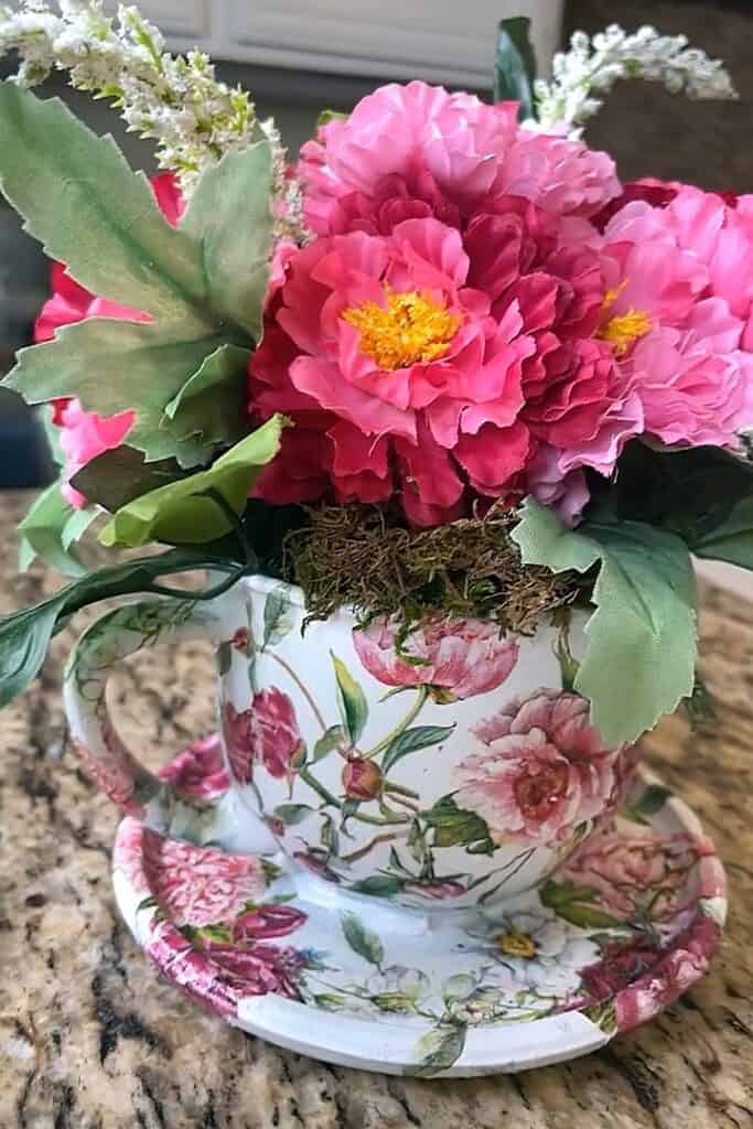 Beautiful pink flowers in a floral teacup with matching saucer, home decor, floral arrangement.