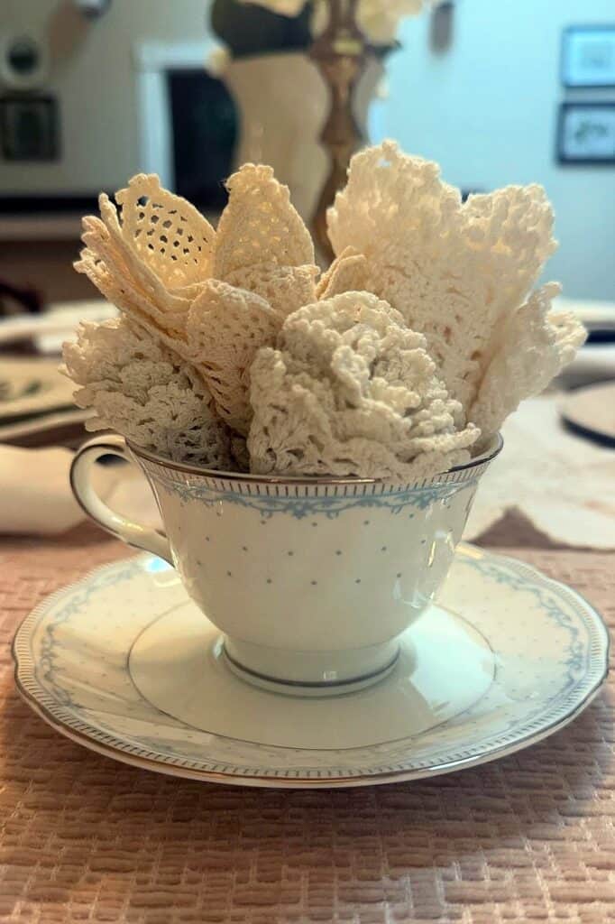 Elegant white lace doilies arranged in a vintage teacup, perfect for tea party decor.