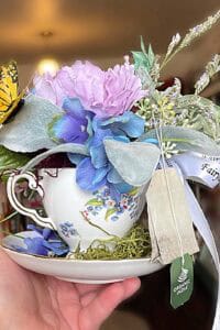 Beautiful organic floral display with lavender, blue, and pink flowers in a teacup.
