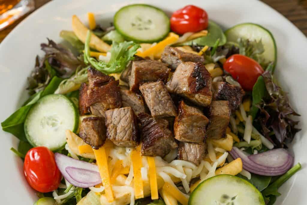 Fresh high-protein steak salad with cucumbers, cherry tomatoes, and mixed greens.