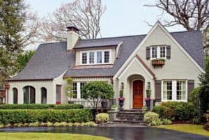Beautiful painted brick house with a red front door and lush landscaping.