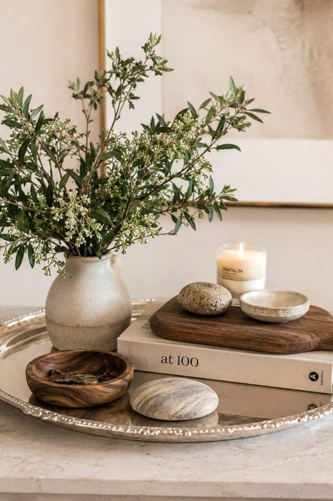 Elegant floral arrangement with candles, stones, and wooden accents for home decor.