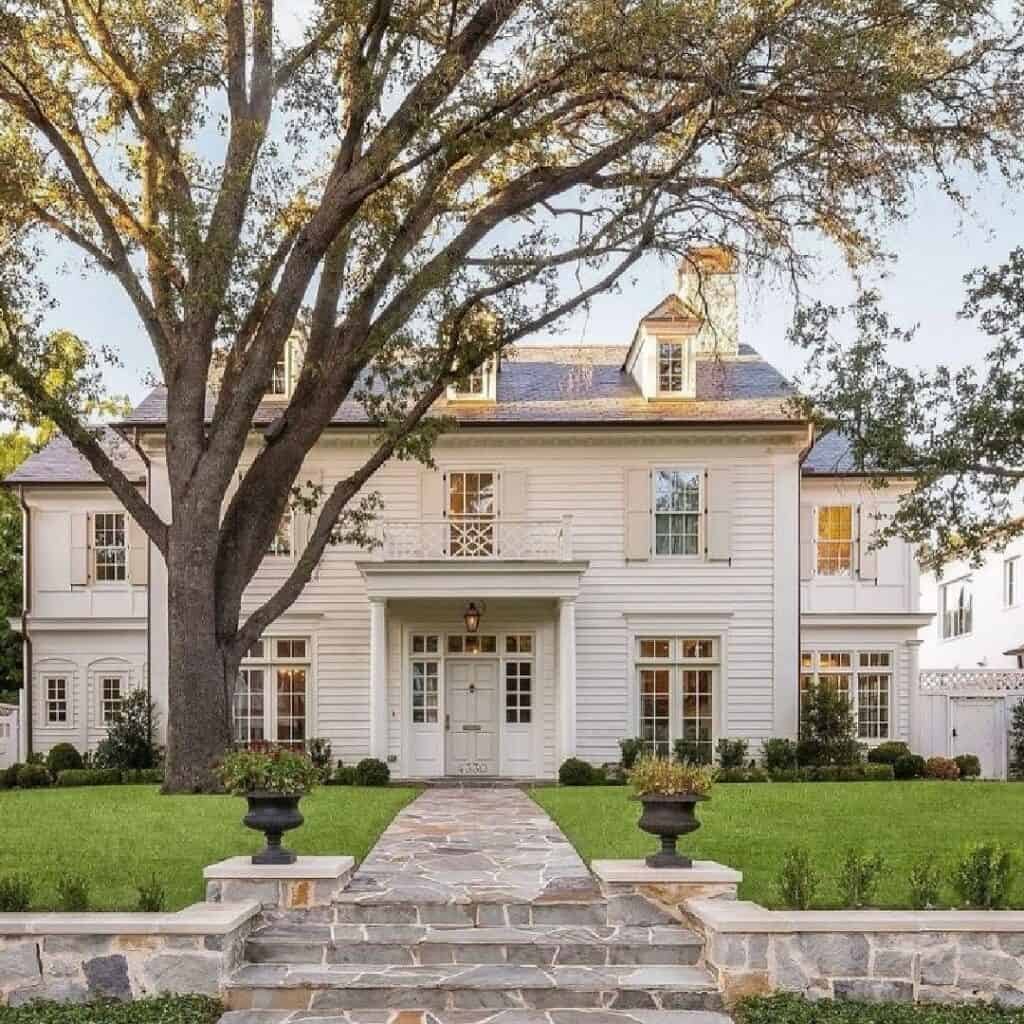 Elegant Victorian house with white exterior, large front yard, and mature tree.