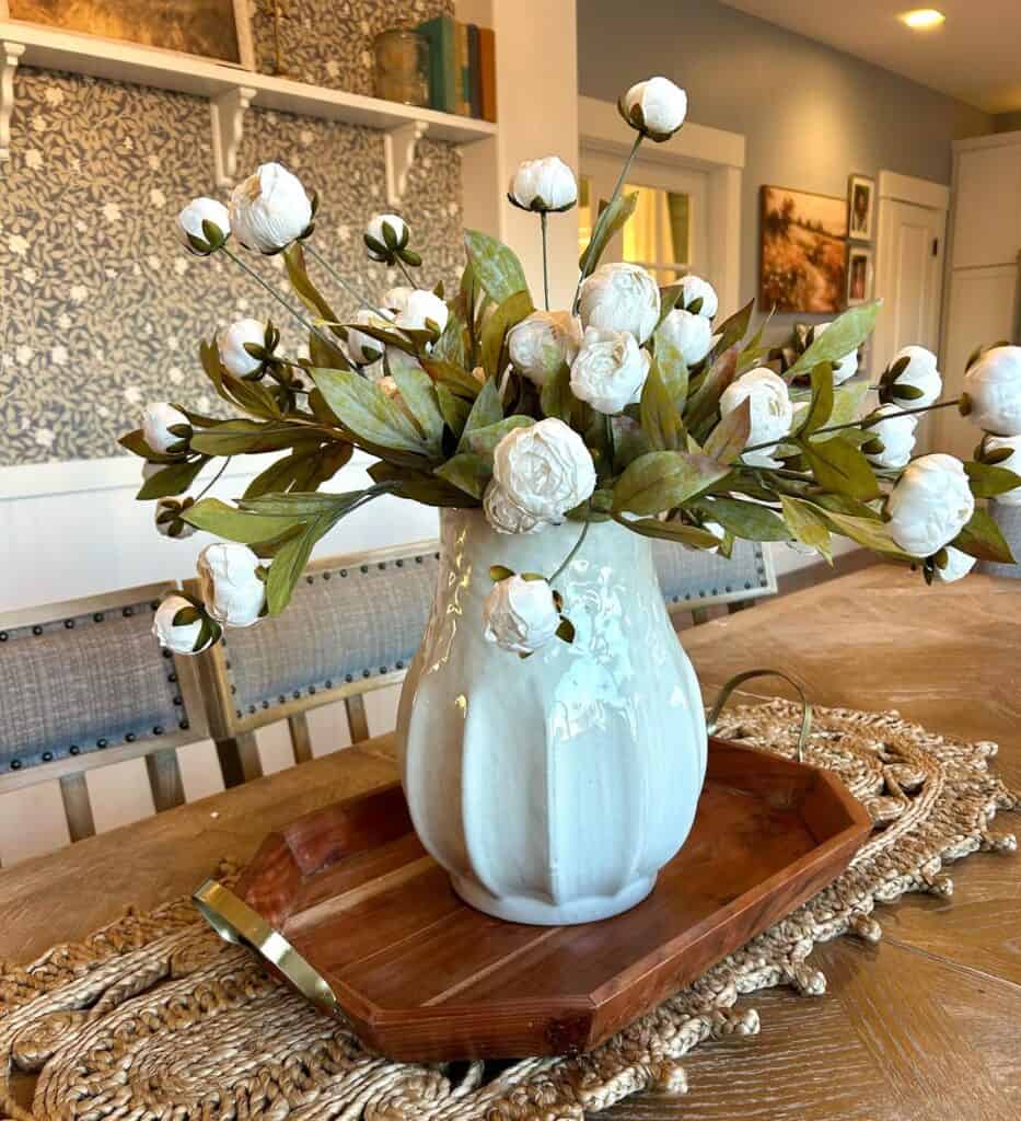 White flower arrangement in a ceramic vase on a wooden table for kitchen decor.