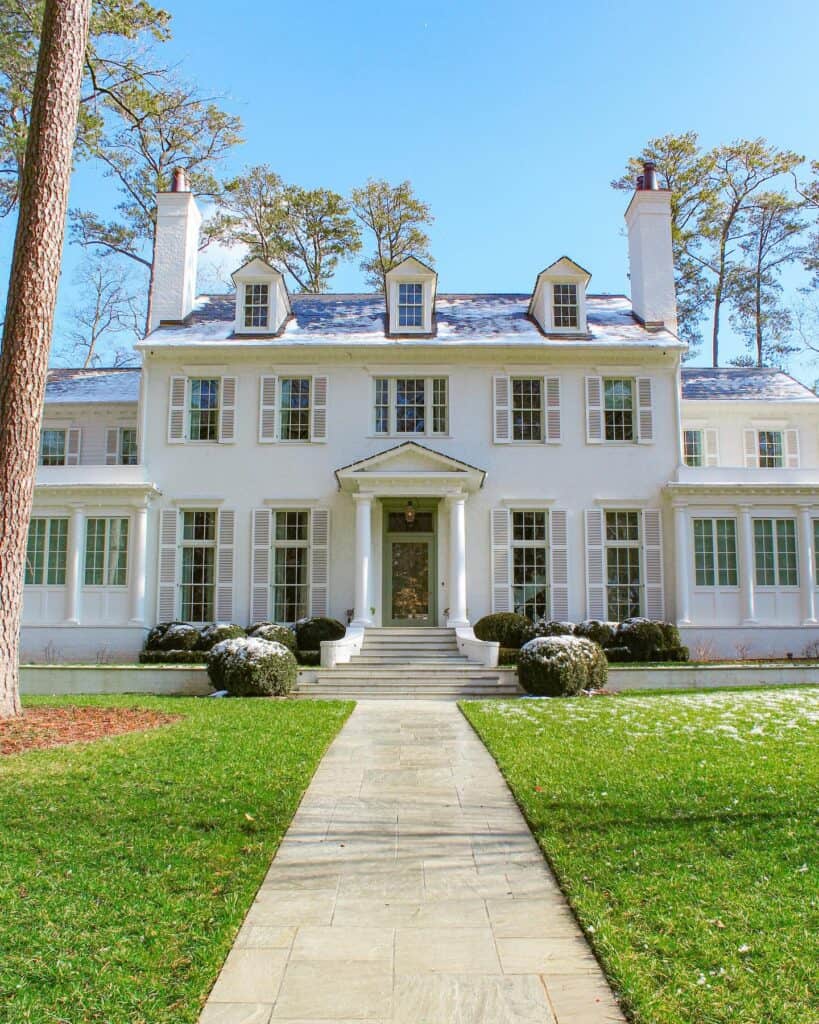 Beautiful white historic mansion with lush green lawn, blue sky, and charming architecture.