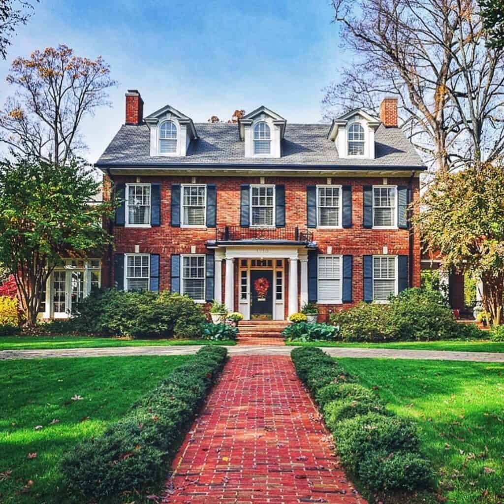 Beautiful historic brick house with lush front yard and fall foliage.