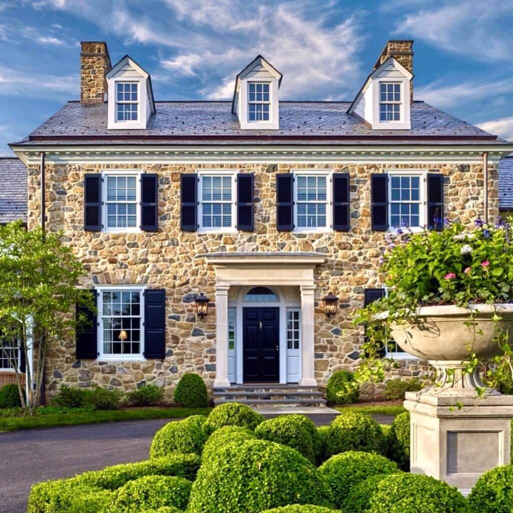 Stone house with blue shutters, manicured garden, and classic architecture